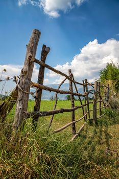 A handmade wooden fence made of thin rods. The old fence of tree trunks, rural landscape, nature wallpaper background.