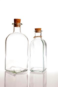 two glass bottles with cork on a white background with reflection