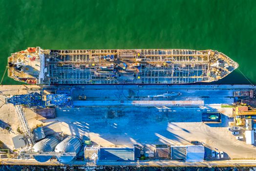 A chemical tanker of the city port. Aerial top view from a drone. Concept export ship