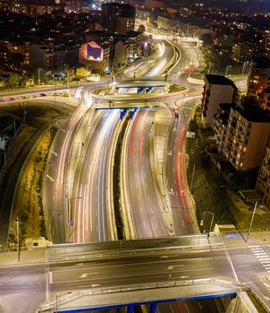 Beautiful night traffic junction road with lights of vehicle movement aerial view from drone. Vertical view