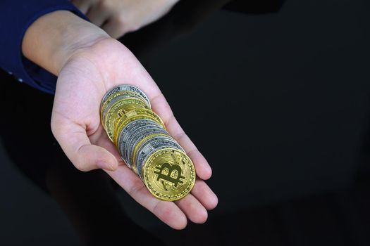 Closeup image of a women holding and giving golden color bitcoins