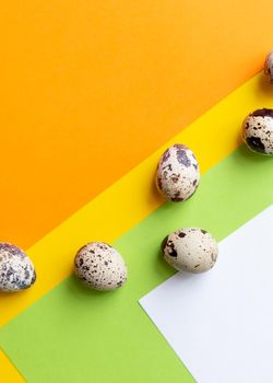 Three quail Easter eggs lying on two beige pastel shades with a hard shadow. Trendy isometric beige background.