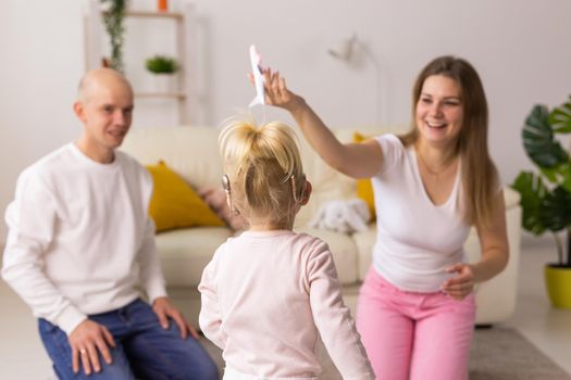 Cochlear implant on the child girl head and playing with mother and father. Hearing aid and deafness and innovative health technology