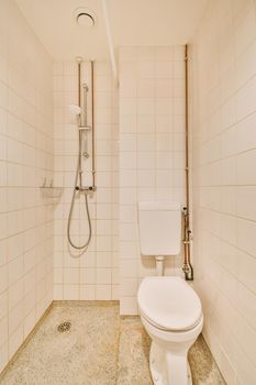 Glass partition between shower tap and wall hung toilet in modern restroom at home