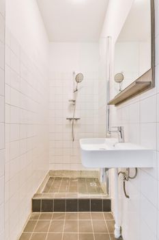 Sinks with mirrors located near shower box with glass door in modern bathroom with white tiled walls