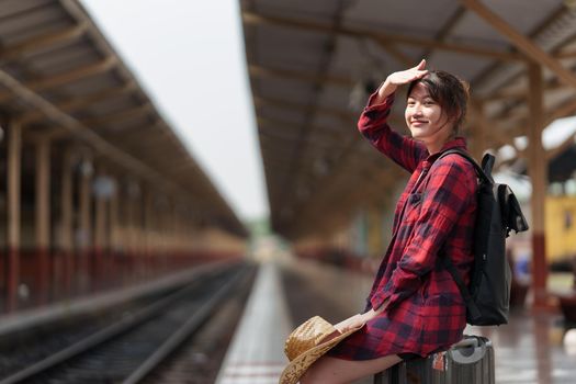 Young traveler woman planning trip at train station. Summer and travel lifestyle concept