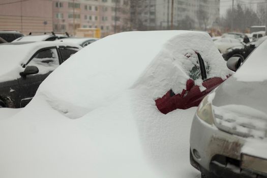 Frozen cars in parking lot. Cars were covered with snow. After snowstorm. Transport under snowdrift.