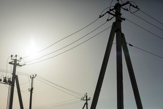 Poles with electrical wires. Silhouettes of communication racks. High voltage lines. Energy transfer. Concrete electric poles.