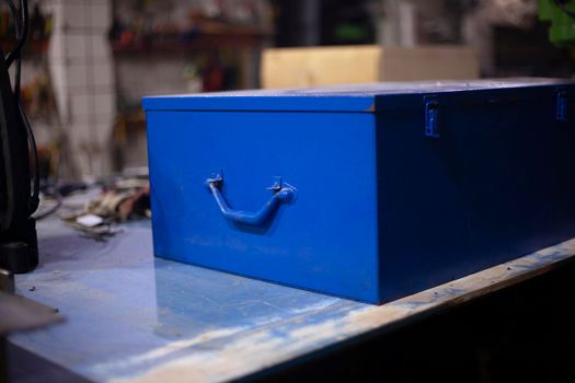 Tool box in blue. An old box lies on the table. Vintage object in the garage. Painted in a blue object.