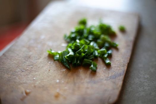 Chopped green onions on board. Ingredient for soup. Small onions are on table. Healthy food with vitamins. Juicy plant in soup. Cutting board.