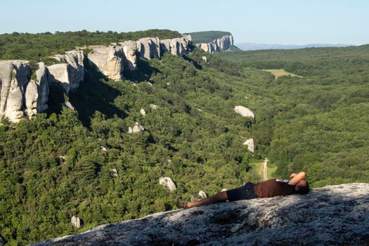 A man walks through a cave city in the summer. Tourists watch the rocks. Rest on top. Tourist route in the Crimea. Crimean mountains in the travel season. Beautiful mountain landscape. On a walk.