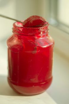 Jam in jar. Red berry in sugar. Jam in natural light. Glass jar with candied berries. Sweet food.