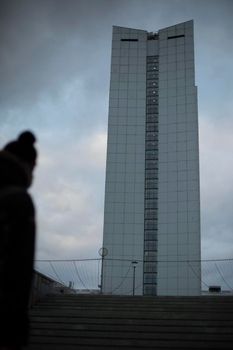 Tall building in city. Silhouette is blurry. House with offices. Urban architecture.