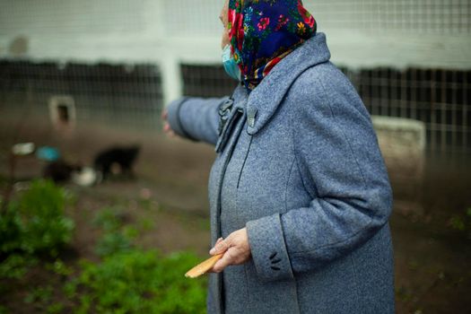 An old woman in Russia. Pensioner in a coat on the street. A woman in a headscarf on her head.