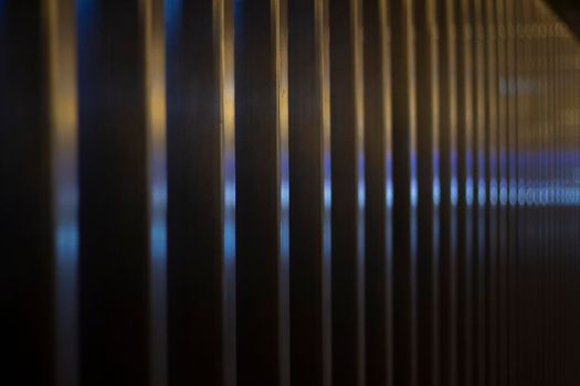 Reflection on metal fence. Warm and cool colors on steel profile. Fence at night. Details of city.