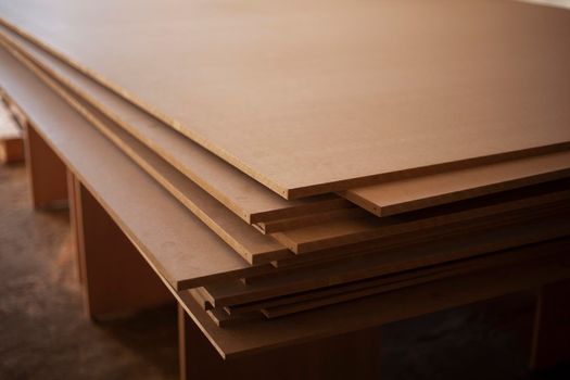 Boards are stacked. Plywood sheet. Joinery. They made furniture production. Building material in garage. Raw wood. Material made of pressed sawdust.