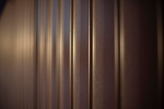 Texture of steel fence. Profile sheet is brown. Fence details. Blurry background in sunlight.