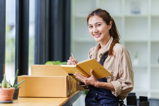 A portrait of Asian woman, e-commerce employee freelance with parcel box for deliver to customer. Online marketing packing box delivery concept
