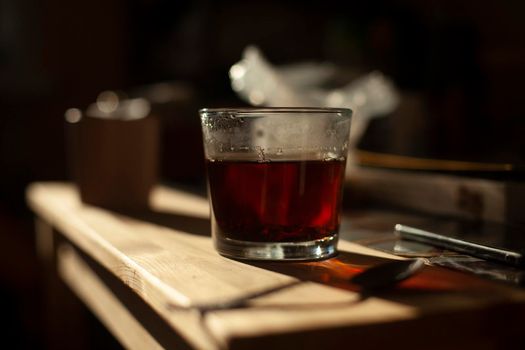 Tea in glass. Kitchen details. Hot drink in morning. Strong black tea. Transparent cup.