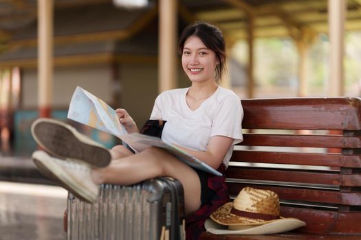 Young traveler woman looking on maps planning trip at train station. Summer and travel lifestyle concept