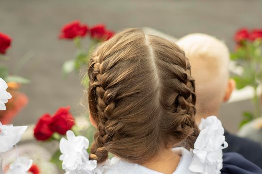 Student with flowers. Schoolgirl at party at school. Girl in Russia on Day of Knowledge. White bows on hair of schoolgirl.