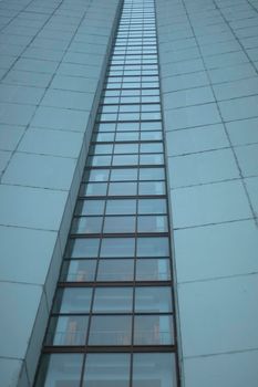 High-rise building on gray day. Architecture details. Surface of wall. Glazing in house.