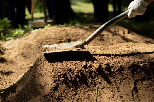 Undertaker strikes grave. Shovel and earth. Man is digging ground. Sand ramming. Garden tools.