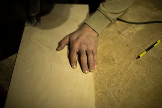 Carpenter holds tree. Worker chooses board. Details of carpentry workshop. Hand of woodworking master.