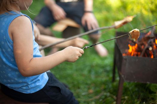 Bread on stick. Cooking at picnic. White piece of bread is strung on sticks made of wood. Frying bread over open fire. Summer outdoor recreation in detail.