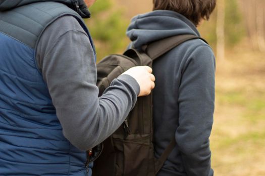 The guy is in a backpack. A man takes things from a friend's bag. A hacker passes something into a bag.