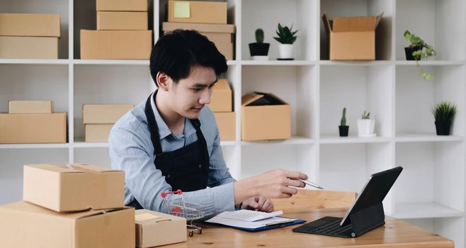 Laptop computer at workplace of start up, small business owner. cardboard parcel box of product for deliver to customer. Online selling, e-commerce, packing concept,work from home.