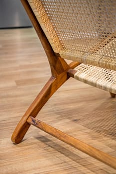 Detail of back part of modern wicker chair standing in a living room with laminate. Interior wooden furniture