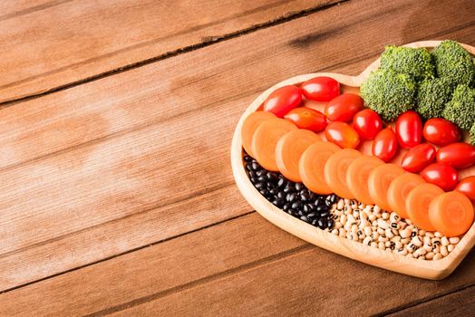 Top view of fresh organic fruits and vegetables in heart plate wood (carrot, Broccoli, tomato) on wooden table, Healthy lifestyle diet food concept