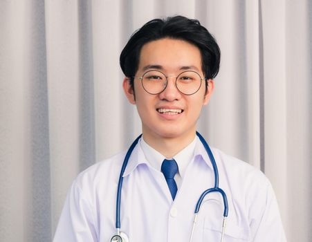 Portrait of Happy Asian young doctor handsome man smiling in uniform with stethoscope talking online video conference call or facetime looking to camera, healthcare medicine concept