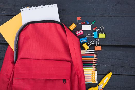 Top view flat lay of red school bag backpack and accessories tools for children education on black wood background, Back to school concept and have copy space for use