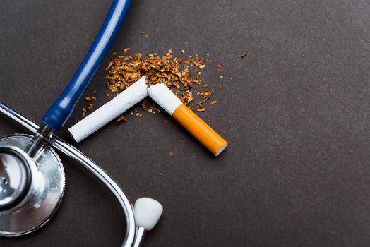 31 May of World No Tobacco Day, no smoking, close up of broken pile cigarette or tobacco and doctor stethoscope on black background with copy space, and Warning lung health concept