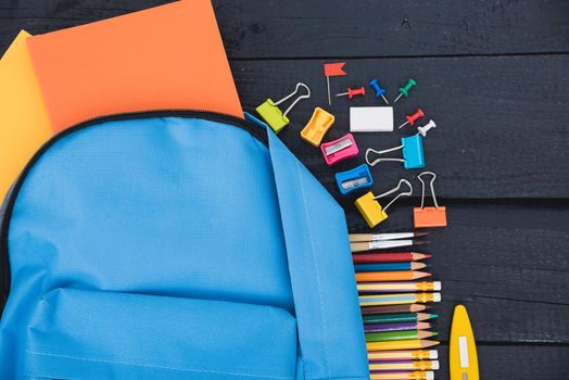 Top view flat lay of blue school bag backpack and accessories tools for children education on black wood background, Back to school concept and have copy space for use