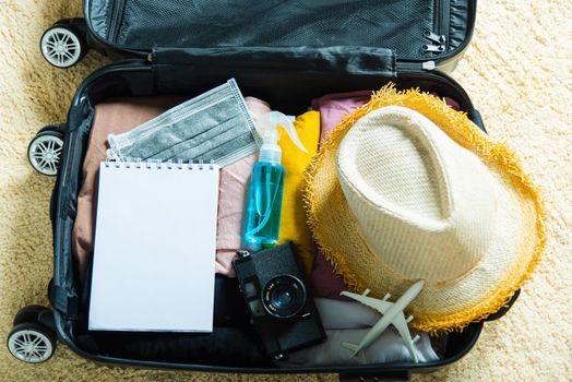 Open suitcase with traveler belongings clothes and accessories of things ready packing to be taken on summer holiday, Travel vacation luggage preparations concept, top view