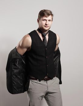 young businessman in a business suit without a shirt holds a jacket over his shoulder.
