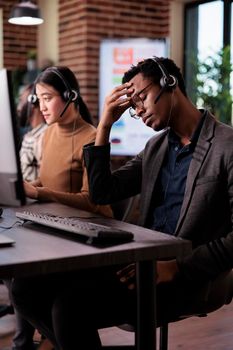 Helpdesk assistant working at call center client care on phone line, using telemarketing equipment. Customer service operator giving support and assistance on helpline telephony network.