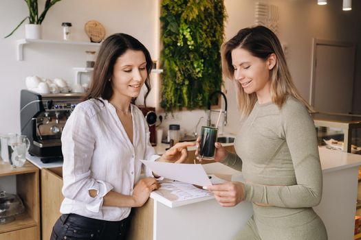 A nutritionist and a girl after fitness classes discuss healthy eating standing in a cafe.