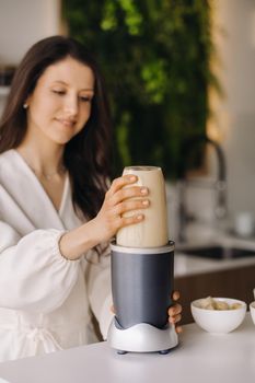 a girl makes a cocktail in a fruit blender in the kitchen. Diet for weight loss.