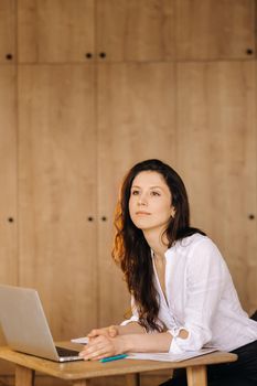 Beautiful woman sitting in the office working on a laptop.