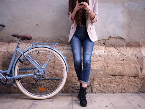 close-up view of a woman chatting on her phone next to her bike in the street, horizontal cut out