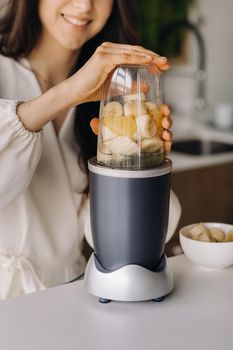 a girl makes a detox cocktail of fruit in the kitchen . Diet for weight loss.