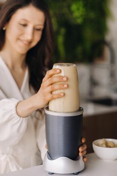 a girl makes a cocktail in a fruit blender in the kitchen. Diet for weight loss.