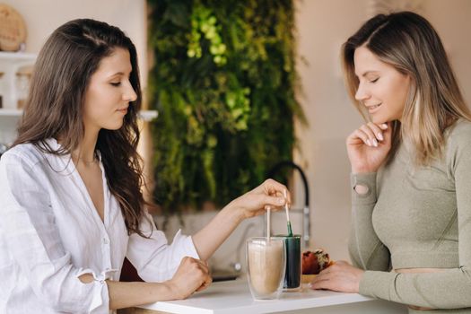 Two sporty-looking girls with cocktails in their hands discuss healthy eating and diet.