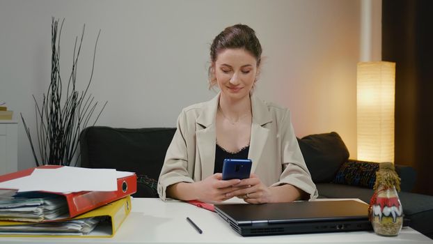 Woman using smartphone after a successful day's work. Chat with a friend and smile.