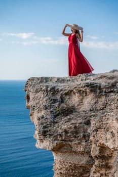 A woman in a red flying dress fluttering in the wind, against the backdrop of the sea