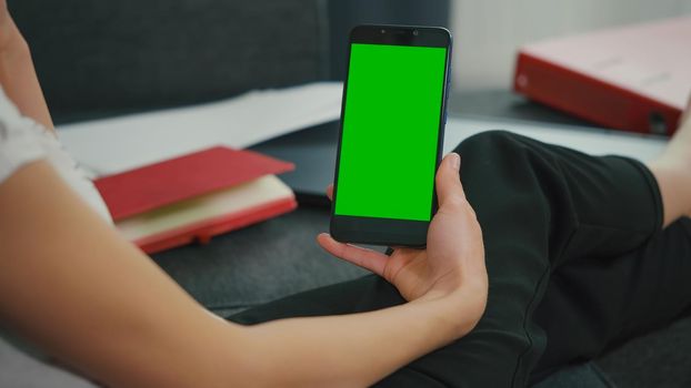 Back View of Woman at Phone with Green Screen for Copy Space. Chromakey Mockup. Girl watching video on couch,